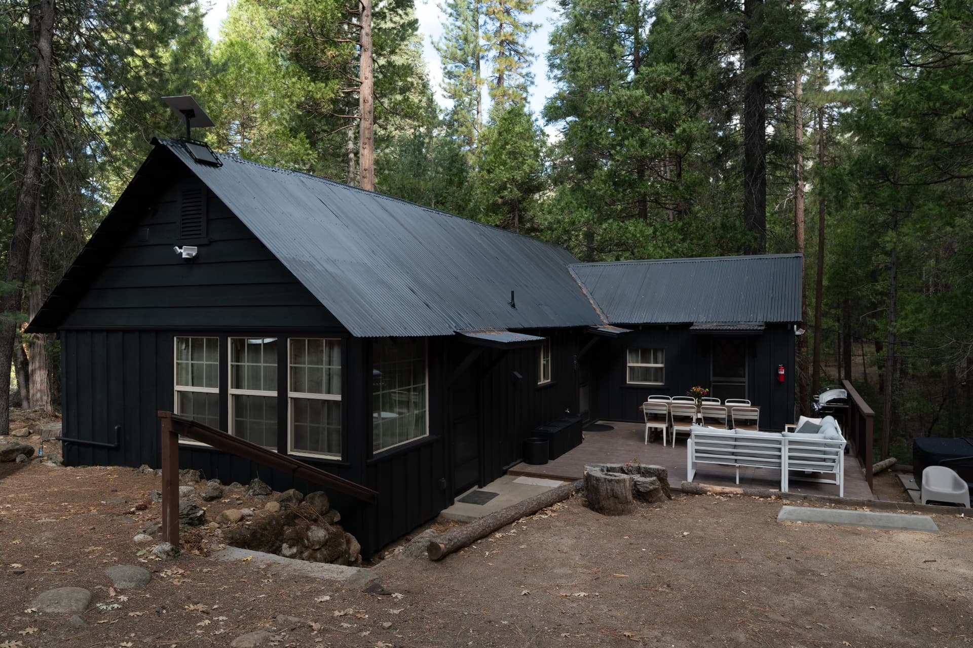 The restored home today, painted charcoal black with the deck set for dinner outdoors