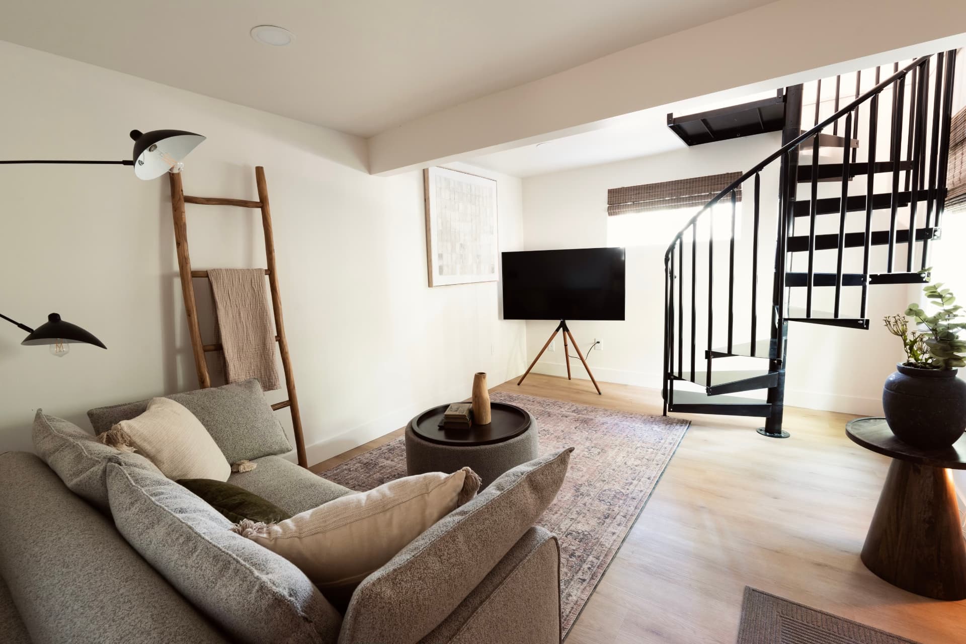 The den today, a bright lounge with a sofa, television and spiral staircase