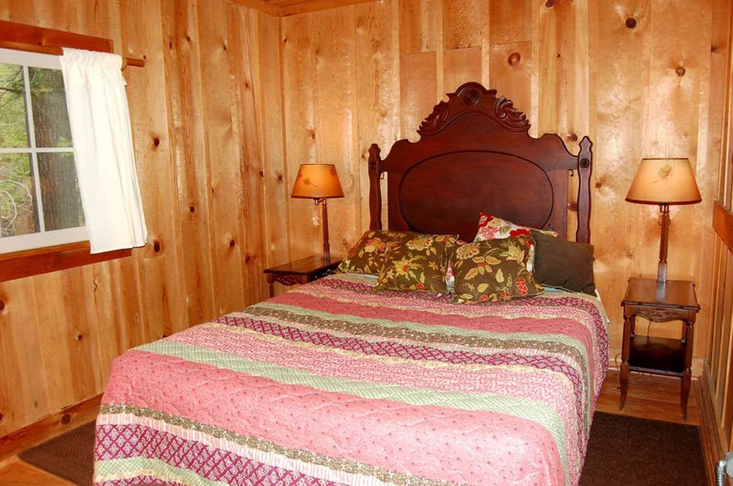 A wood-paneled bedroom with a pink and green quilt