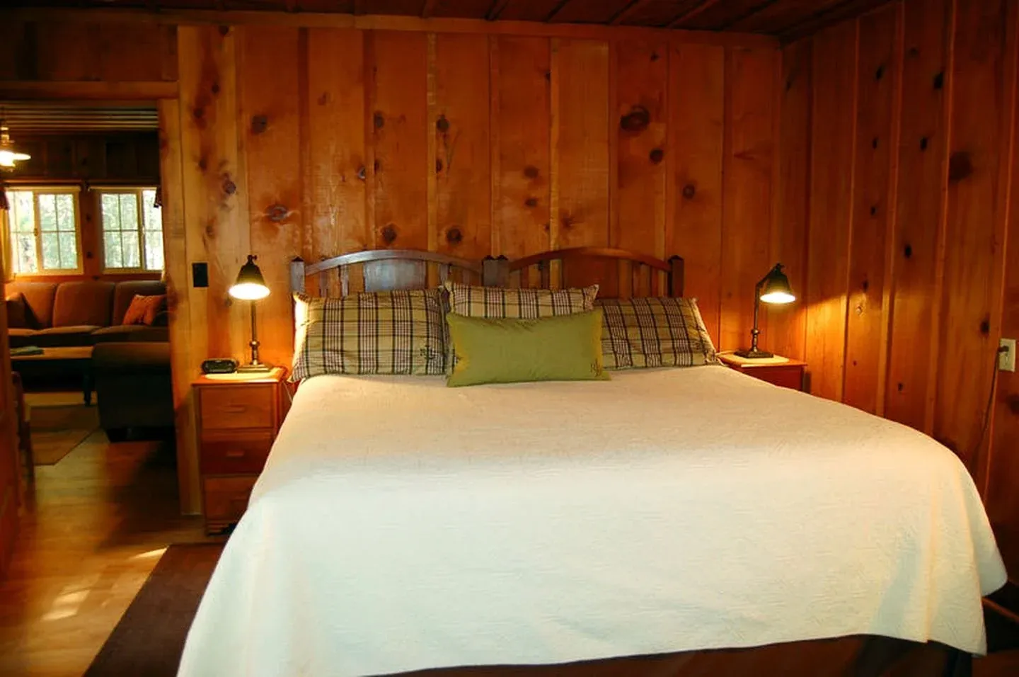 An original wood-paneled bedroom with a white quilt and plaid pillows