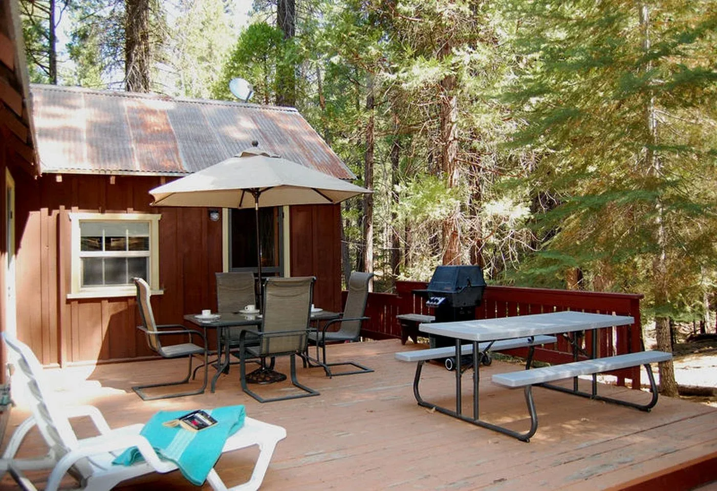 The original deck with patio furniture and a grill among the trees