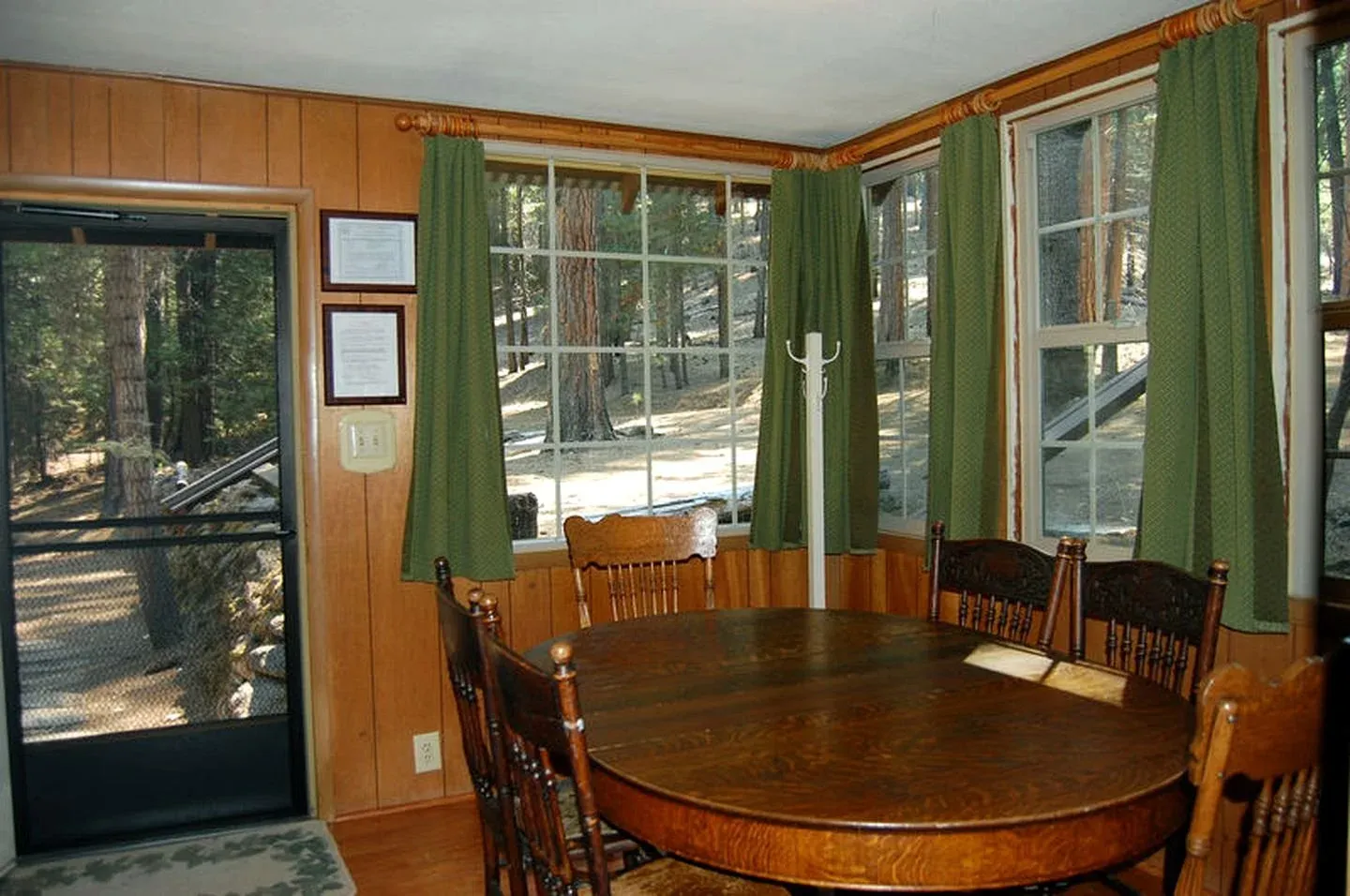 Wood-paneled dining area with a round table and green curtains