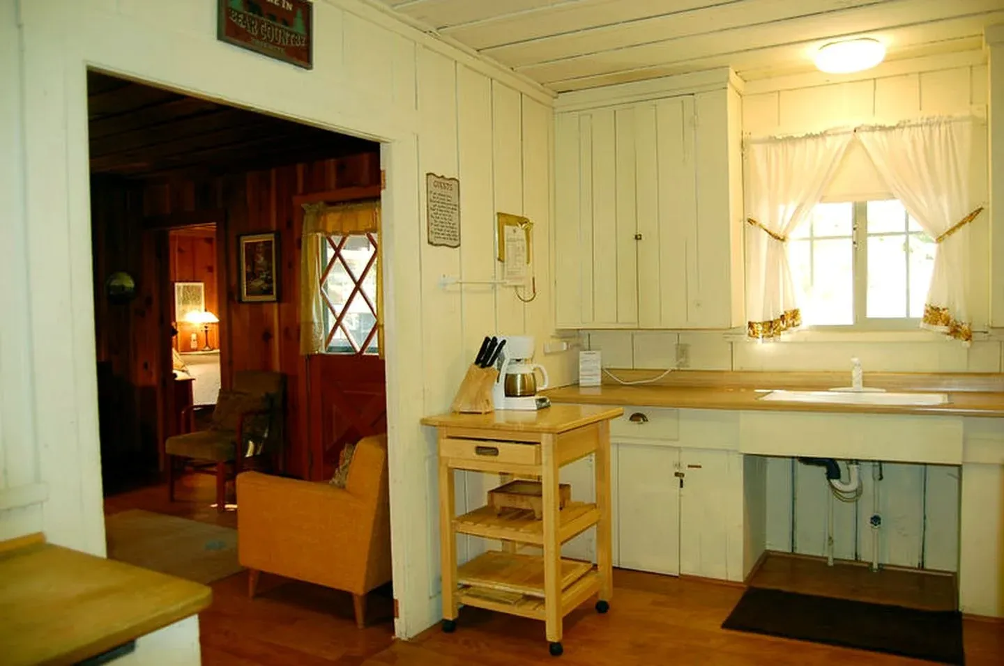 A cozy kitchen with white paneled walls and a wooden countertop