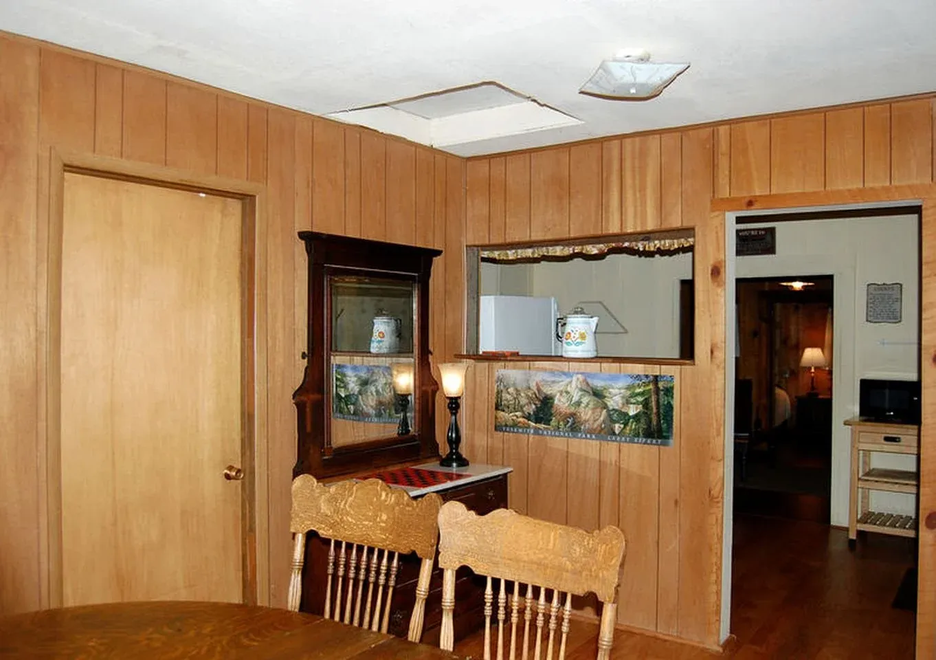 Living room with wood panel walls, a dining table and a framed landscape