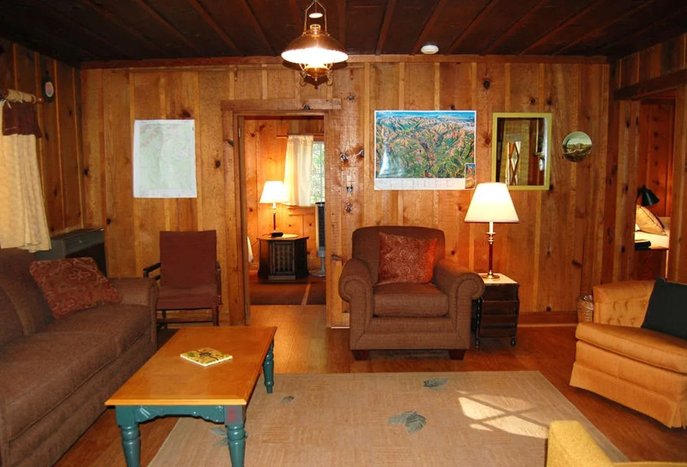 The original wood-paneled living room with armchairs and sofa